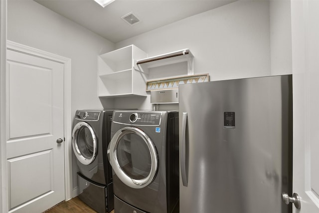laundry room with washing machine and dryer, dark wood finished floors, visible vents, and laundry area