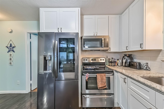 23001 Fresca St, Galveston, TX 77554 - kitchen featuring stainless steel appliances, white cabinetry, and light stone countertops
