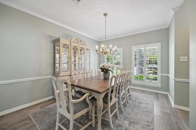 dining room with an inviting chandelier, ornamental molding, wood finished floors, baseboards, and a textured ceiling
