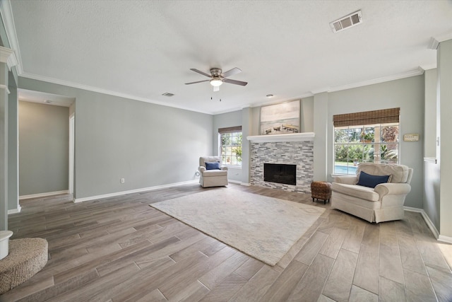 living area with ceiling fan, visible vents, wood finished floors, and a fireplace