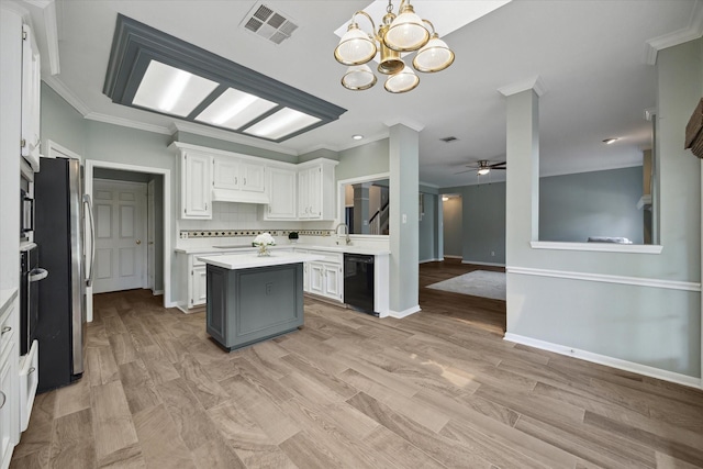 kitchen with light countertops, a center island, black dishwasher, freestanding refrigerator, and visible vents