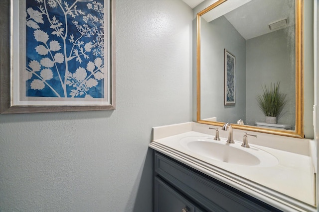 bathroom featuring vanity, a textured wall, and visible vents