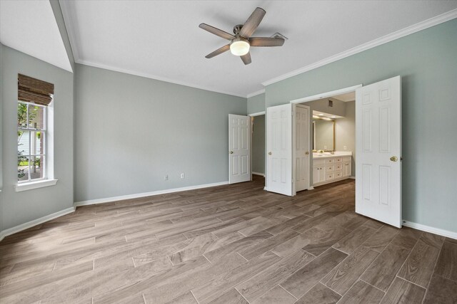 unfurnished bedroom with ornamental molding, baseboards, wood tiled floor, ceiling fan, and ensuite bath