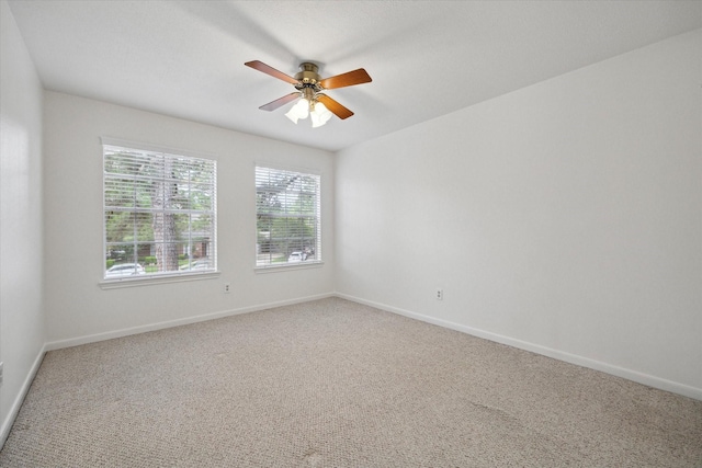 carpeted spare room featuring baseboards and ceiling fan