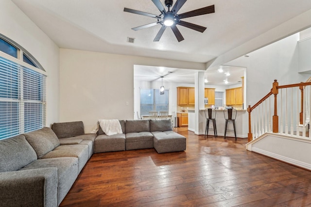 living room featuring a ceiling fan, dark wood-type flooring, and stairs
