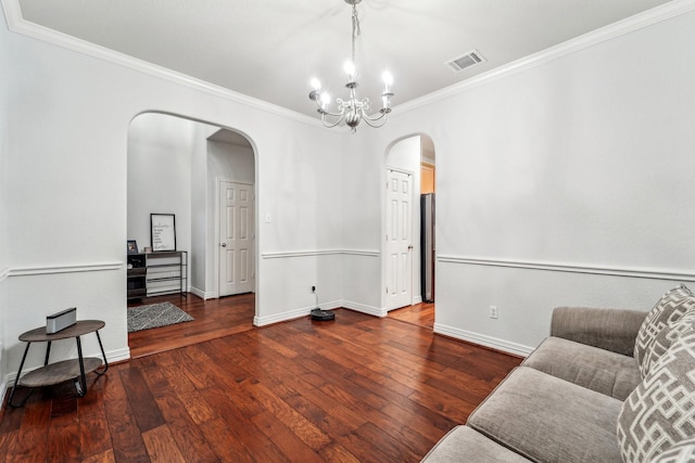 living room featuring arched walkways, ornamental molding, a chandelier, hardwood / wood-style floors, and baseboards