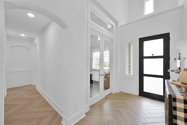 foyer entrance with arched walkways, baseboards, and recessed lighting