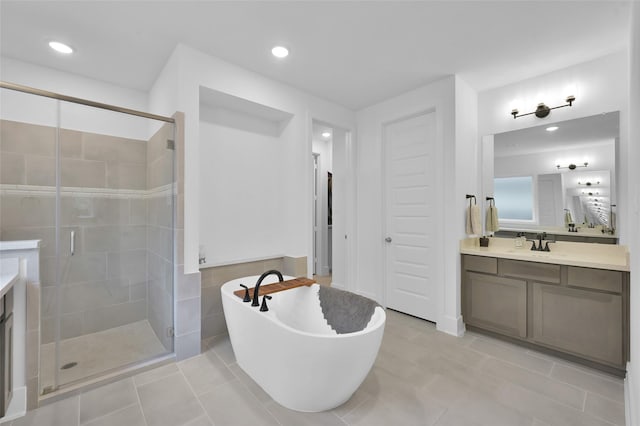 bathroom featuring a freestanding bath, a stall shower, recessed lighting, tile patterned flooring, and vanity