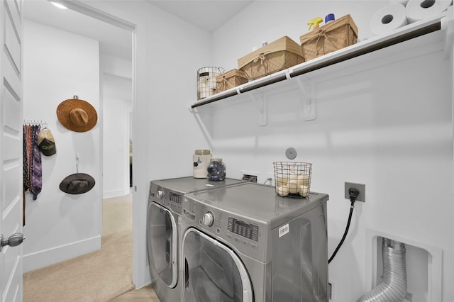 clothes washing area with light colored carpet, washer and dryer, baseboards, and laundry area