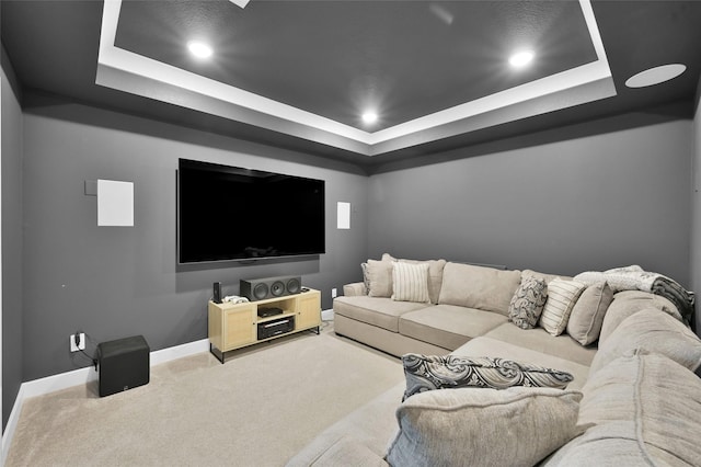 home theater room featuring baseboards, light colored carpet, recessed lighting, and a raised ceiling