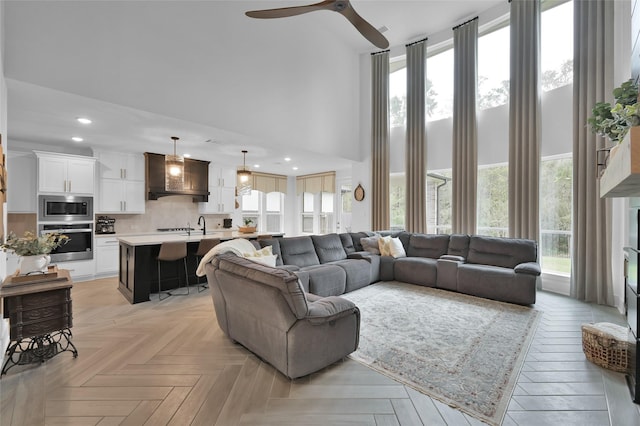 living room with ceiling fan, a wealth of natural light, a high ceiling, and recessed lighting