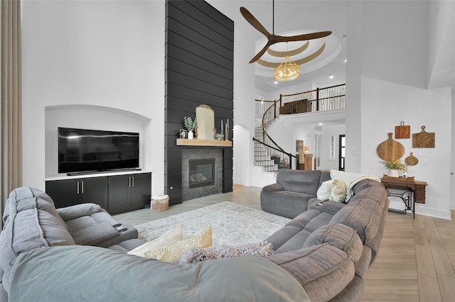 living area featuring a fireplace, baseboards, a towering ceiling, and stairs