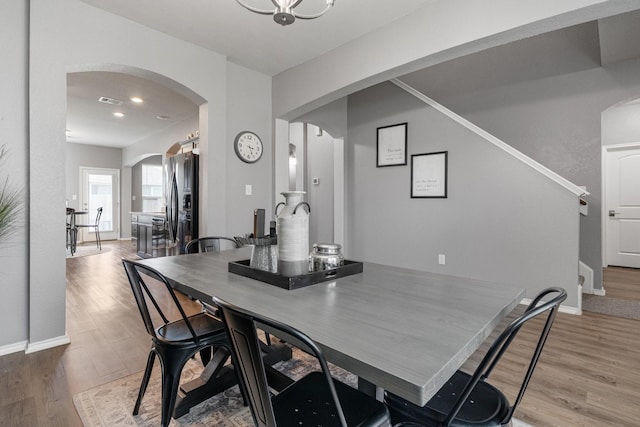 1962 Briar Grove Dr, Conroe, TX 77301 - dining area with arched walkways, light wood finished floors, baseboards, stairs, and recessed lighting