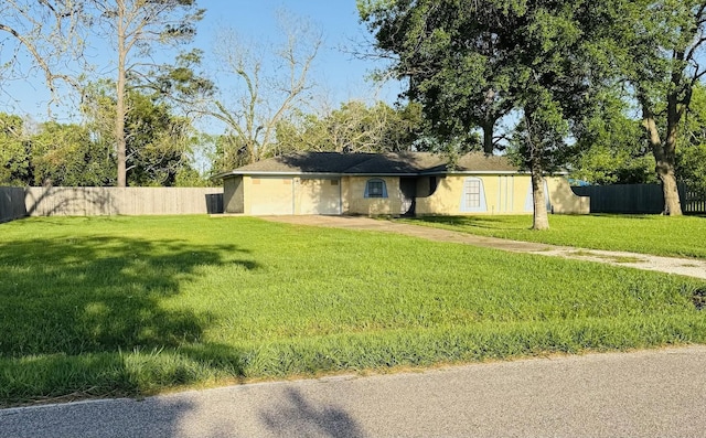 view of front of house with fence, driveway, a front lawn, and stucco siding