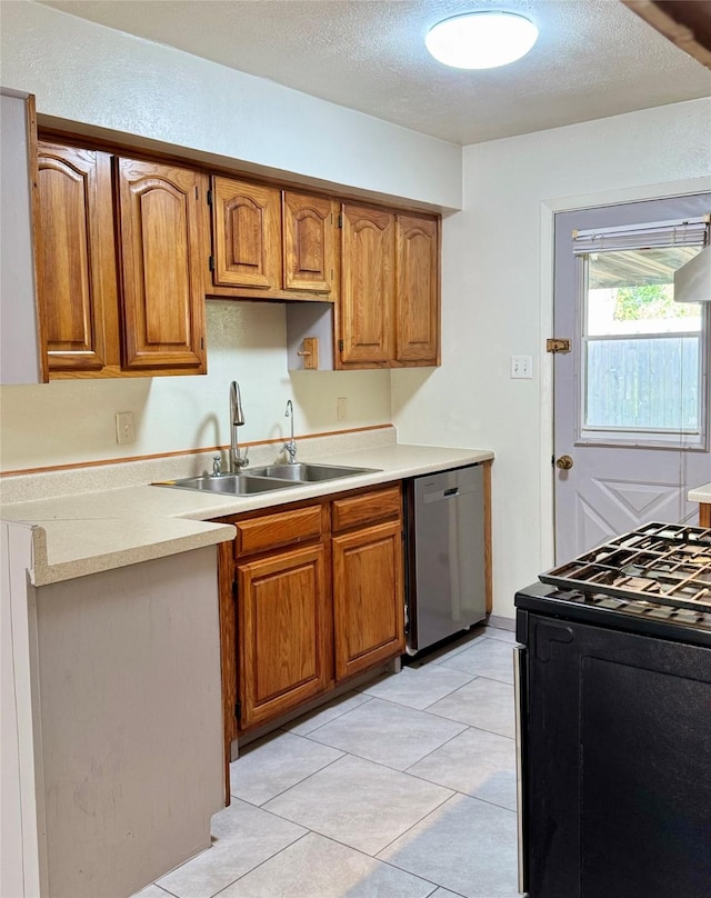 kitchen featuring light countertops, dishwasher, a sink, brown cabinetry, and black range with gas cooktop