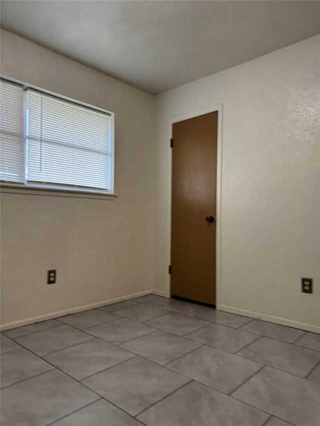 empty room with baseboards and light tile patterned floors