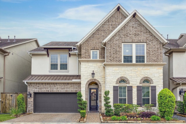 view of front of property with fence, stone siding, a garage, stucco siding, and driveway
