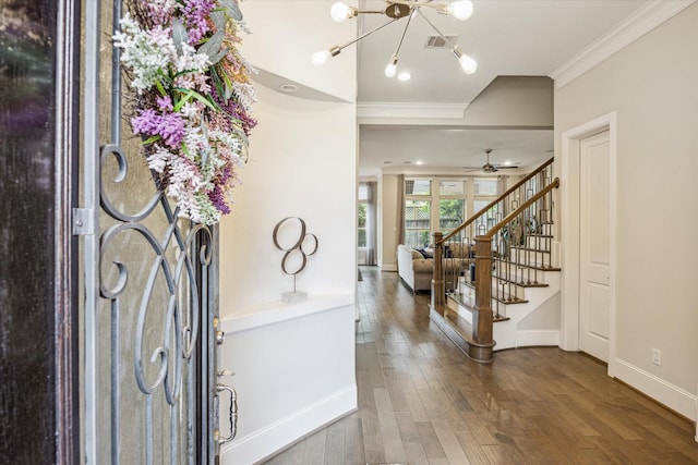 foyer featuring visible vents, crown molding, wood finished floors, stairway, and ceiling fan with notable chandelier