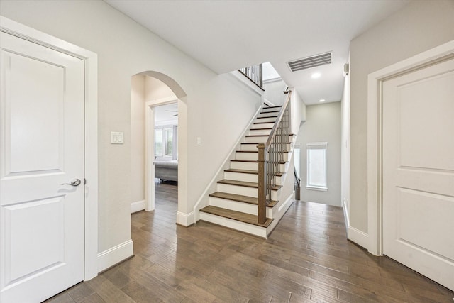 stairway with visible vents, baseboards, recessed lighting, hardwood / wood-style flooring, and arched walkways