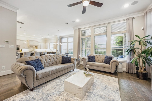 living room featuring plenty of natural light, ornamental molding, and ceiling fan with notable chandelier