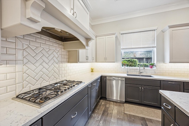 kitchen with a sink, stainless steel appliances, white cabinetry, tasteful backsplash, and ornamental molding