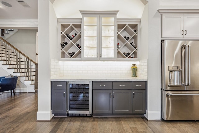bar featuring visible vents, high quality fridge, a bar, beverage cooler, and stairs
