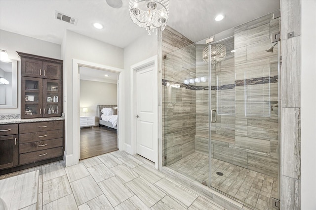 bathroom featuring a chandelier, a shower stall, visible vents, and vanity