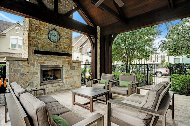 view of patio / terrace featuring fence, a ceiling fan, and an outdoor living space with a fireplace