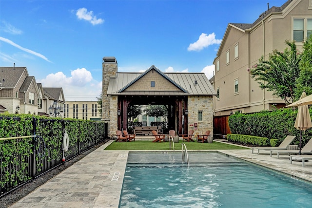 back of property with a standing seam roof, a chimney, metal roof, a gazebo, and a fenced backyard