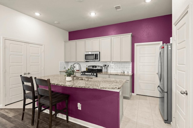 16231 Westley Ridge Dr, Hockley, TX 77447 - kitchen with appliances with stainless steel finishes, tasteful backsplash, a sink, white cabinets, and a center island with sink