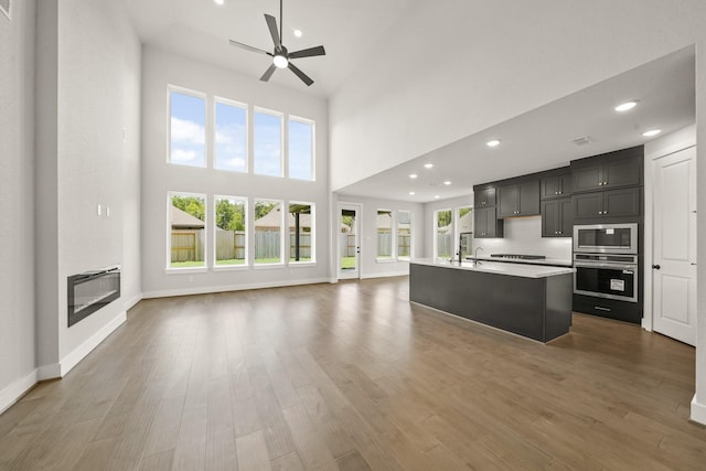 21806 Gateway Arch Dr, Porter, TX 77365 - kitchen featuring appliances with stainless steel finishes, open floor plan, a ceiling fan, light countertops, and a high ceiling