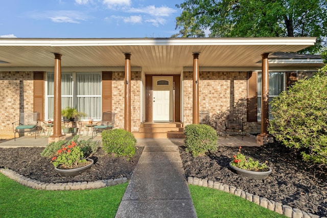 entrance to property featuring brick siding and a porch