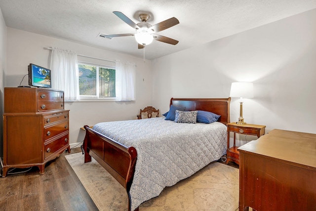 bedroom with a ceiling fan, wood finished floors, and visible vents