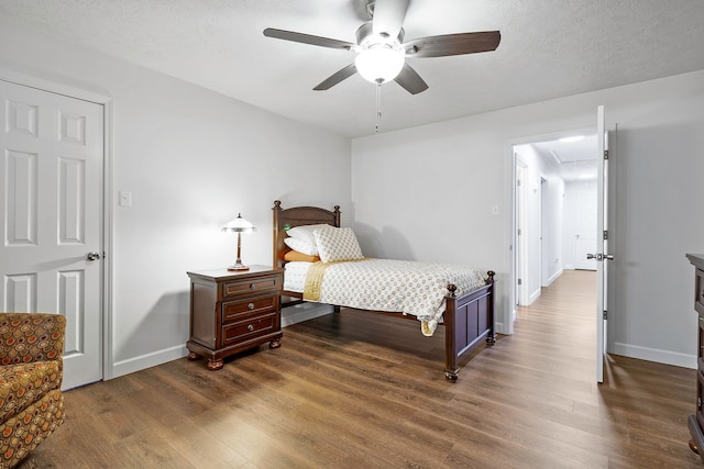 bedroom featuring attic access, dark wood finished floors, baseboards, and a ceiling fan