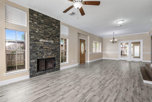 unfurnished living room featuring crown molding, wood finished floors, ceiling fan with notable chandelier, a fireplace, and visible vents