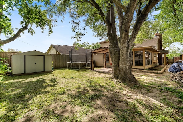 view of yard with a shed, a trampoline, a fenced backyard, an outdoor structure, and a sunroom