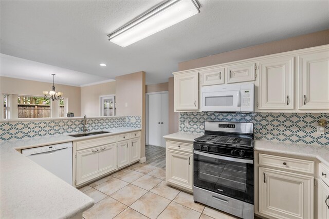 kitchen featuring light countertops, backsplash, a sink, white appliances, and a chandelier