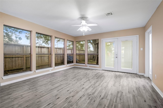 unfurnished sunroom featuring wood finished floors, visible vents, a deck, and french doors