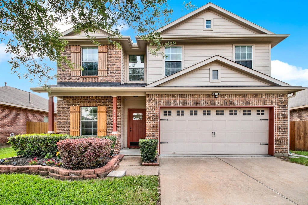 view of front of house featuring brick siding, driveway, and fence