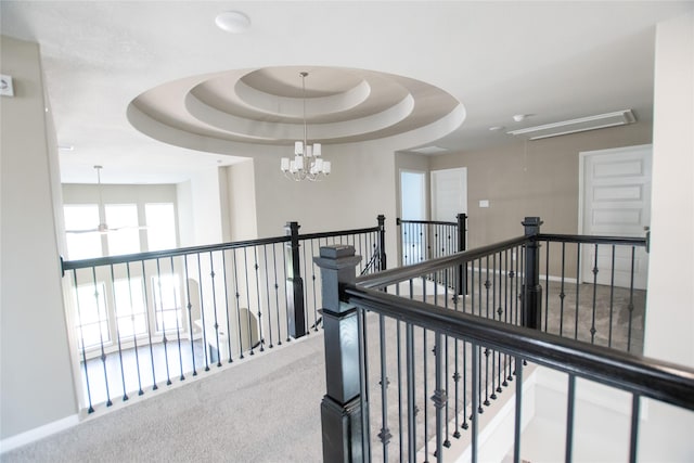 hallway with attic access, carpet floors, an upstairs landing, and a chandelier