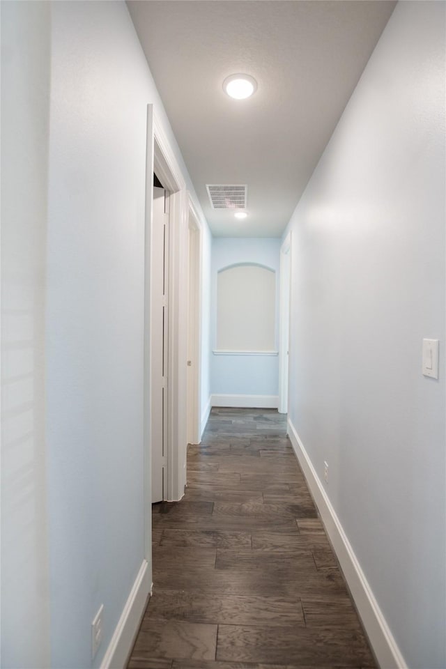 hall featuring baseboards, wood finished floors, and visible vents