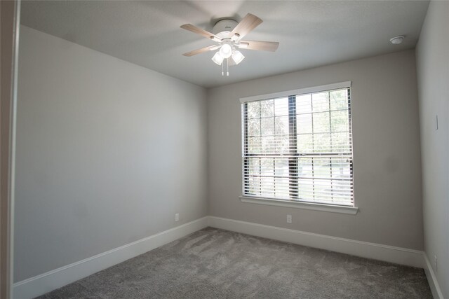 carpeted spare room featuring a healthy amount of sunlight, baseboards, and ceiling fan