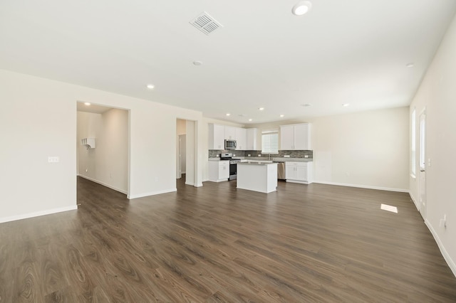 unfurnished living room featuring dark wood-style flooring, baseboards, and recessed lighting