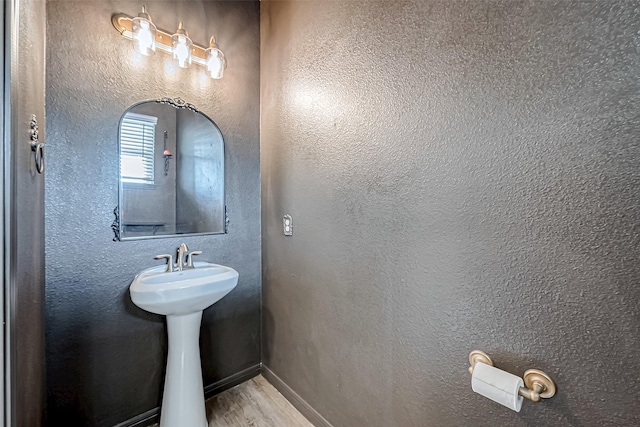bathroom featuring a textured wall, wood finished floors, and a sink