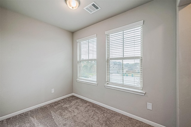 carpeted empty room featuring baseboards and visible vents