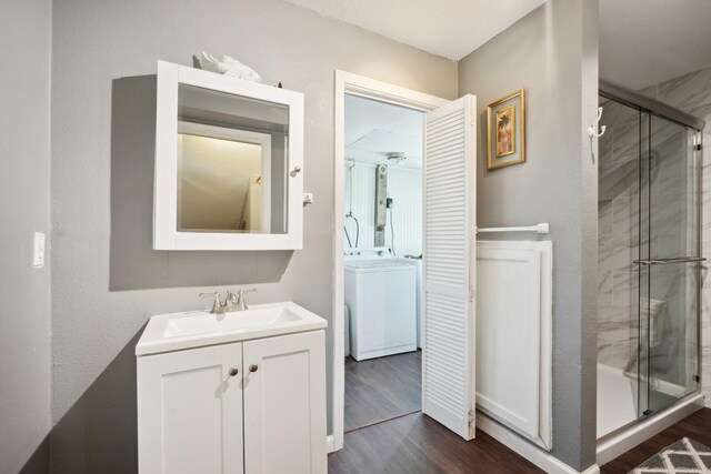 4211 San Jacinto Dr, Galveston, TX 77554 - bathroom with a shower stall, washer / clothes dryer, vanity, and wood finished floors