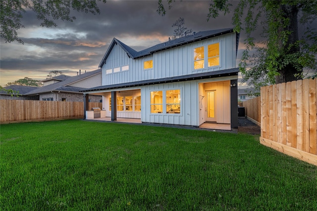 back of property featuring board and batten siding, a lawn, and a fenced backyard