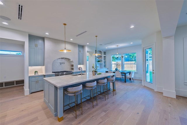 kitchen with light wood finished floors, a sink, a spacious island, visible vents, and recessed lighting