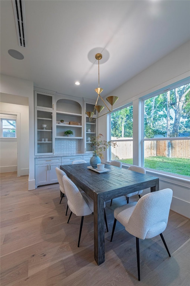 dining room with light wood-type flooring, visible vents, and baseboards