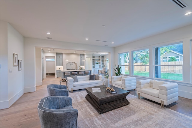 living area featuring light wood-type flooring, baseboards, recessed lighting, and visible vents